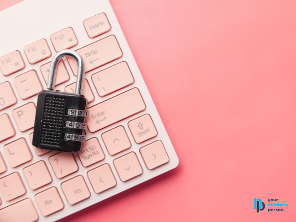 combination lock laying on a computer keyboard with a pink background fraud prevention tips