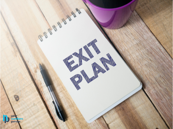 pad of paper on a desk that says exit plan with a pen and coffee cup next to it